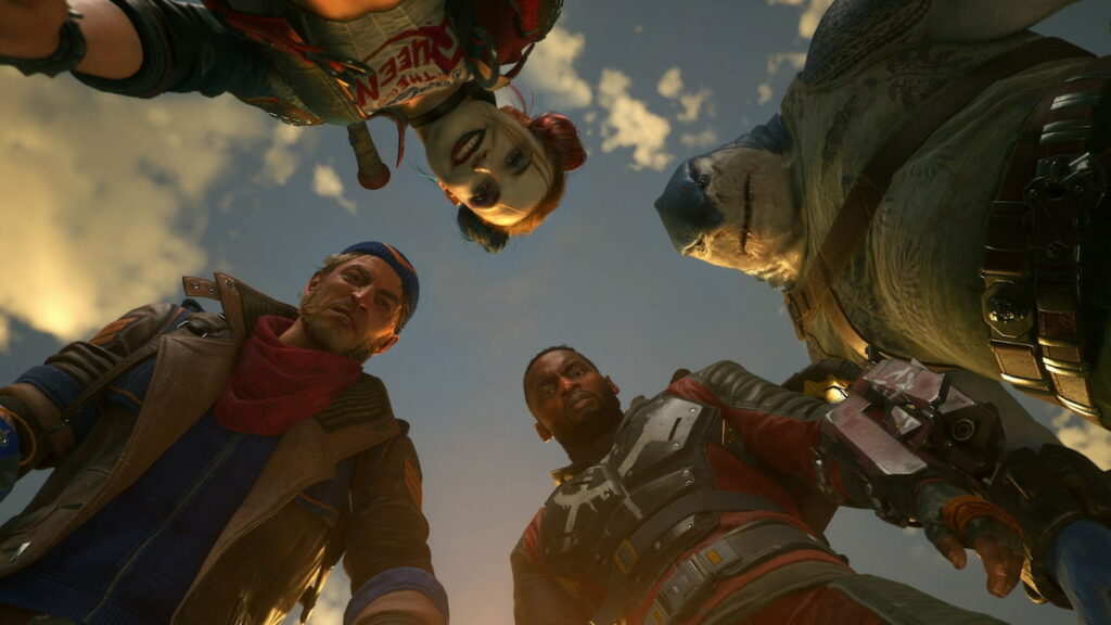 The four main characters of Suicide Squad: Kill The Justice League stand up and look down at the camera, which is looking up at them. The characters are Harley Quinn, Deadshot, King Shark, and Captain Boomerang.
